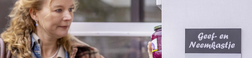 Dame pakt of plaatst iets in weggeefkastje