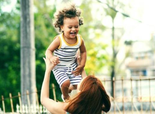 Decoratieve foto van een moeder die haar lachende kind optilt