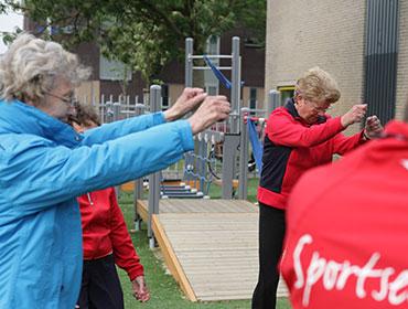 Ouderen sporten buiten onder begeleiding